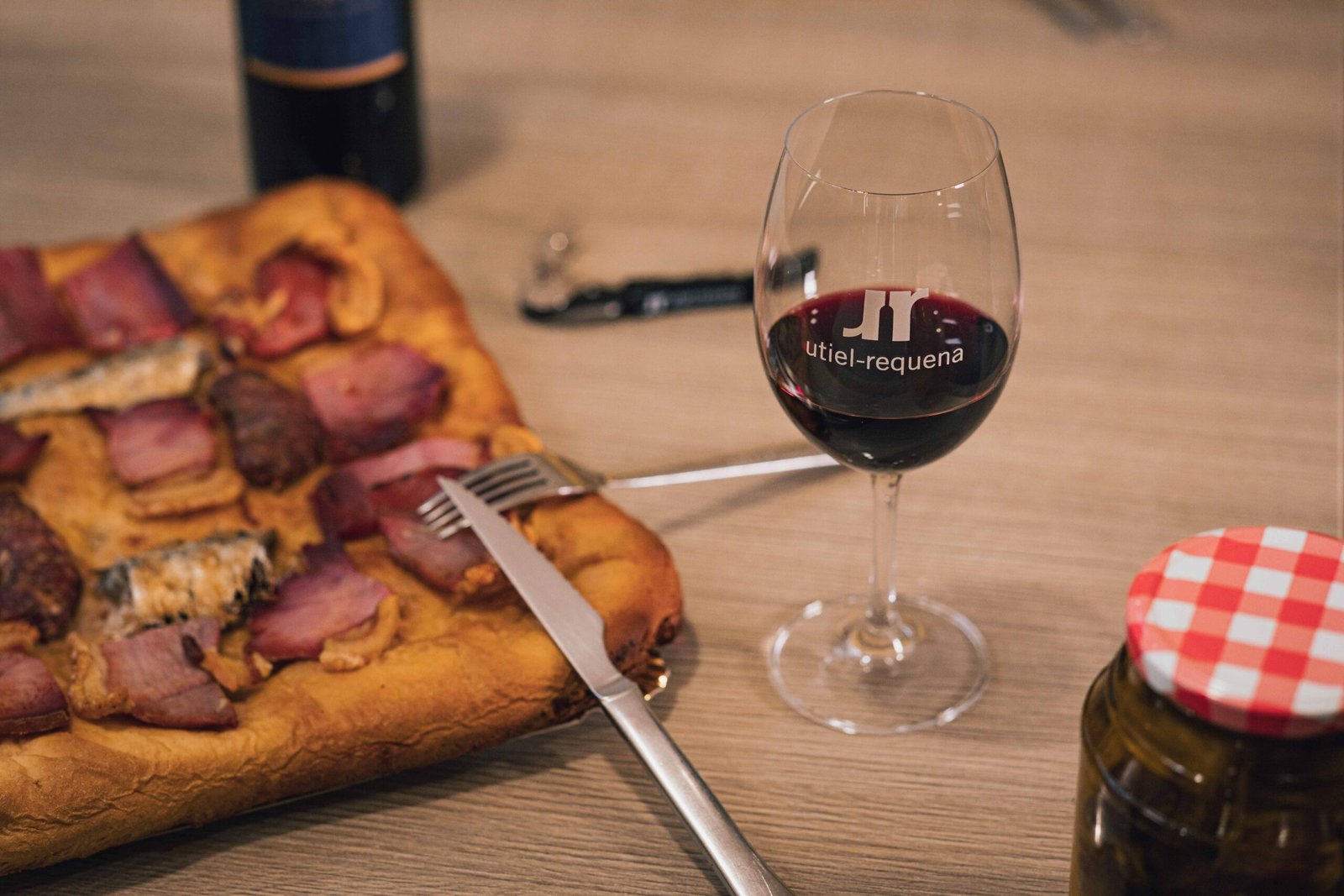 Coca con embutido de la comarca servida junto a una copa de vino tinto