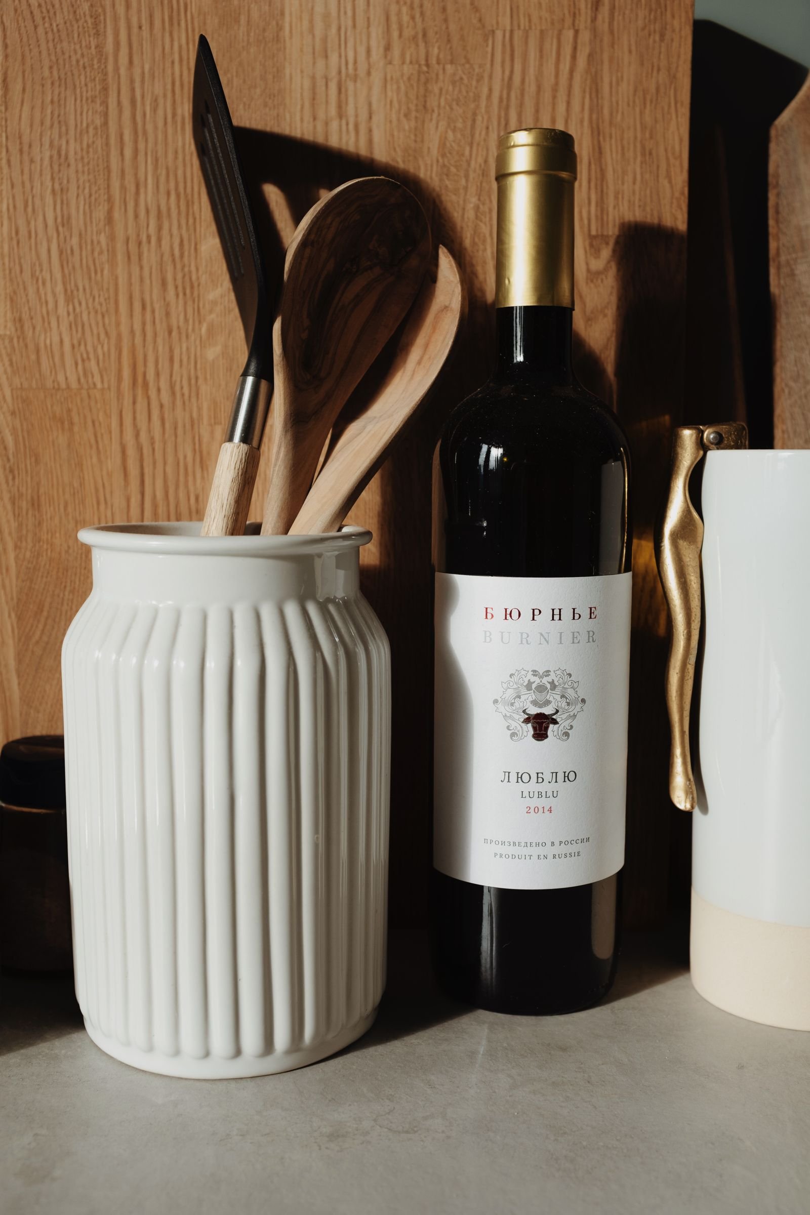 Botella de vino tinto en la cocina junto a utensilios lista para cocinar
