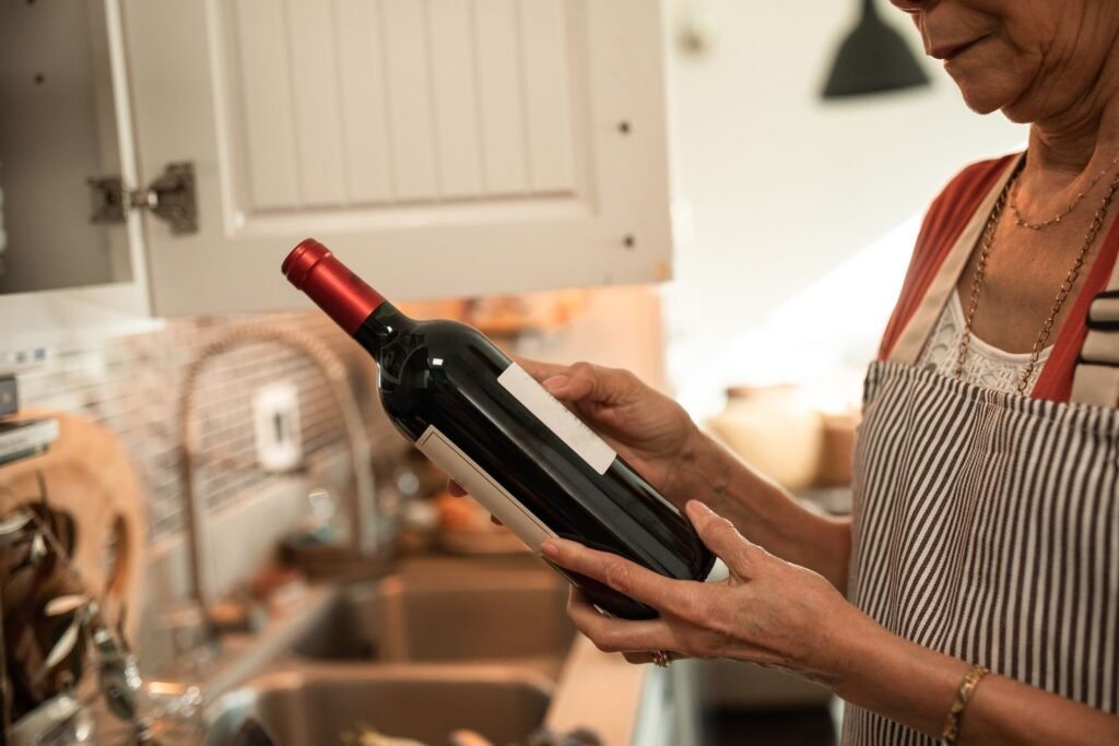 Mujer en la cocina sujetando una botella de vino tinto empezada