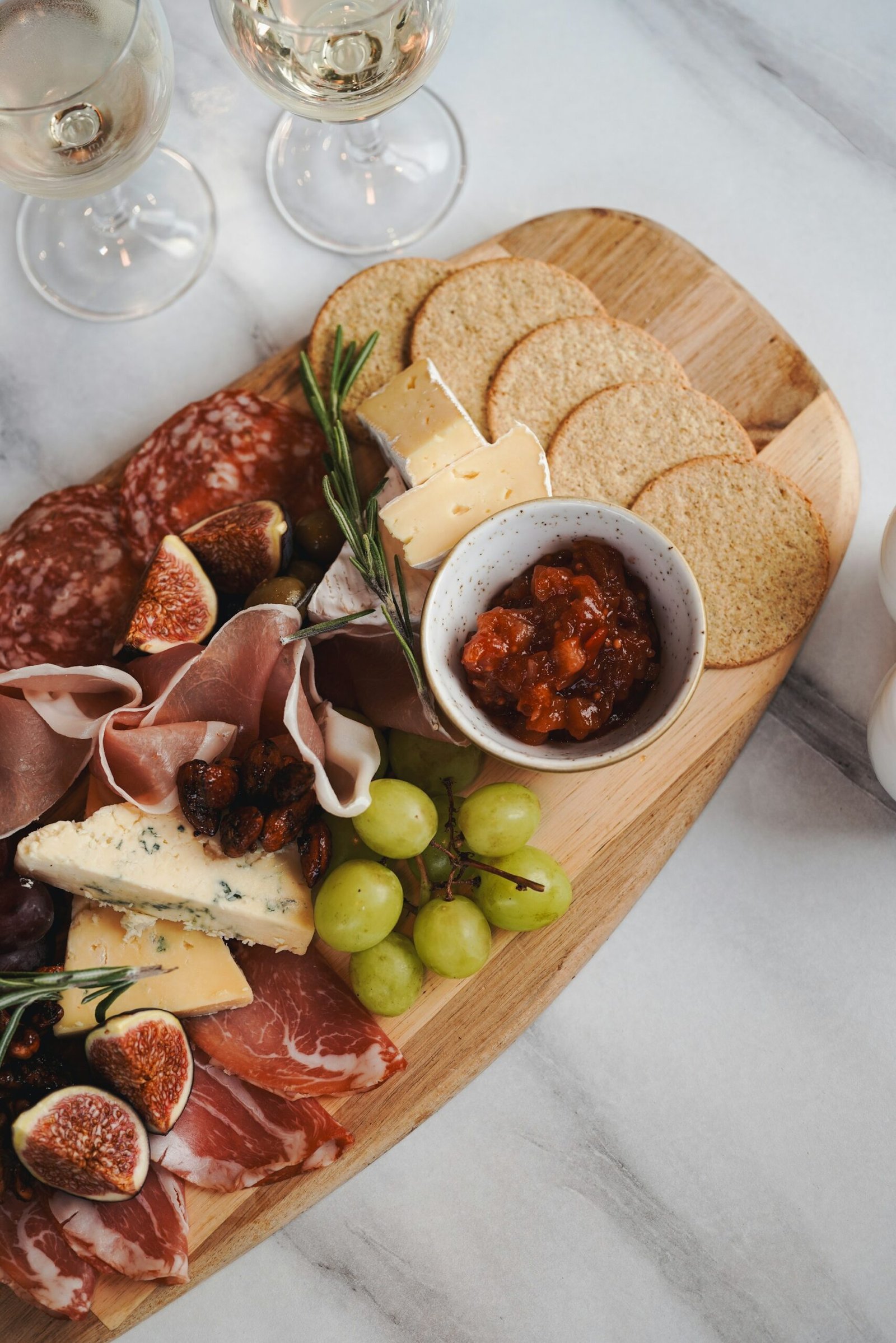Tabla de picoteo con jamón, salami, quesos, uvas y crackers para maridar con vino