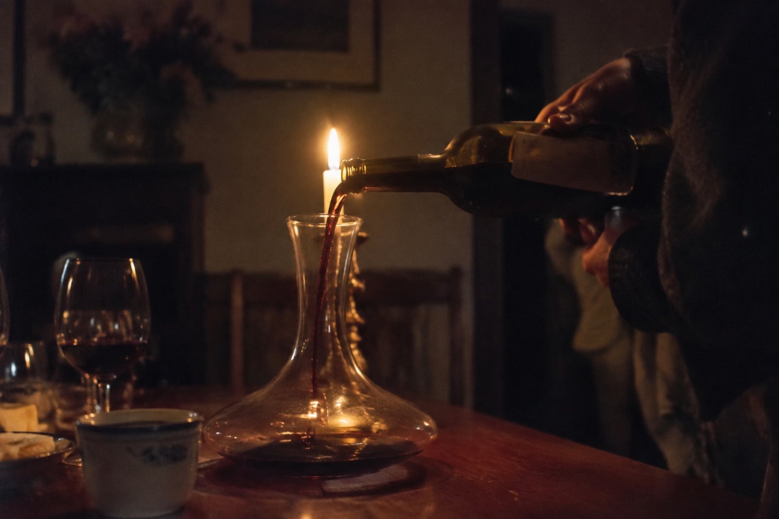 Decantando una botella de vino tinto a la luz de una vela para ver llegar el poso al cuello