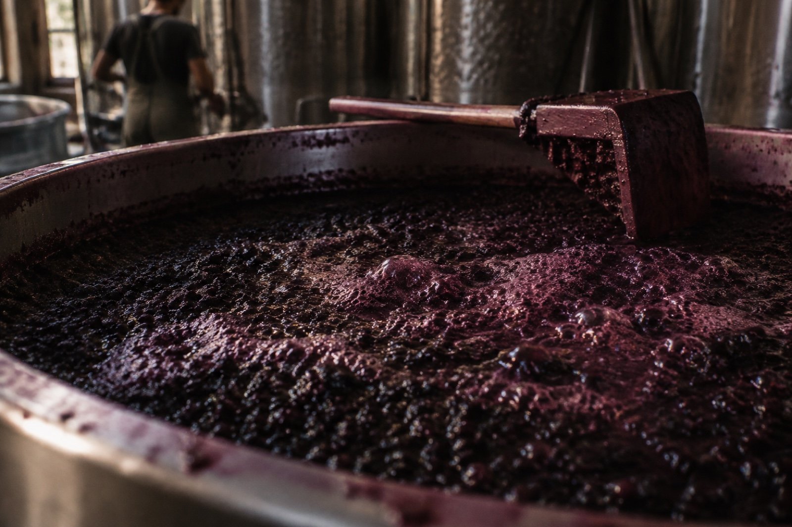 Superficie de mosto tinto fermentando con burbujas de anhídrido carbónico en el depósito