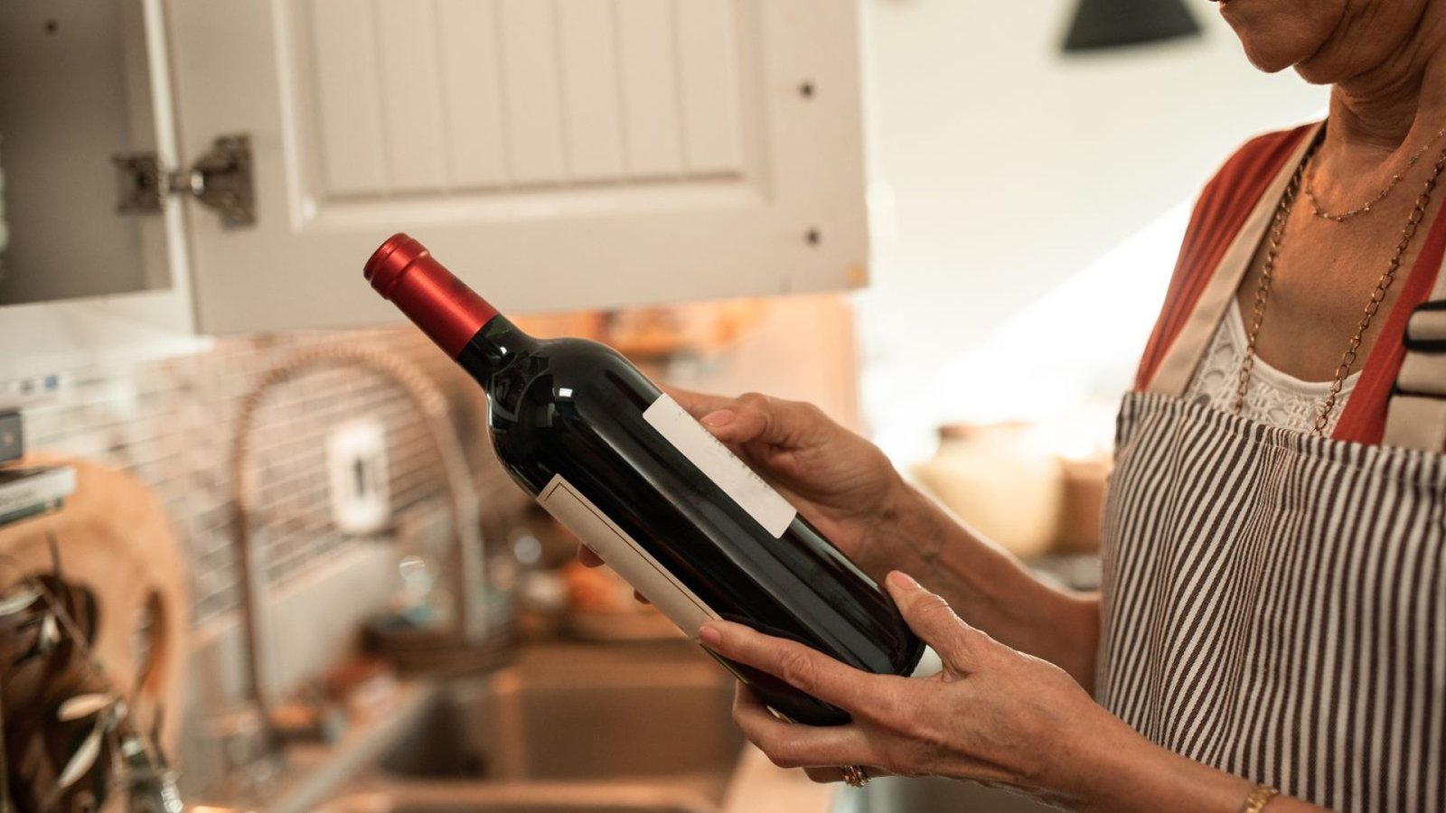 Mujer en la cocina sujetando una botella de vino tinto empezada