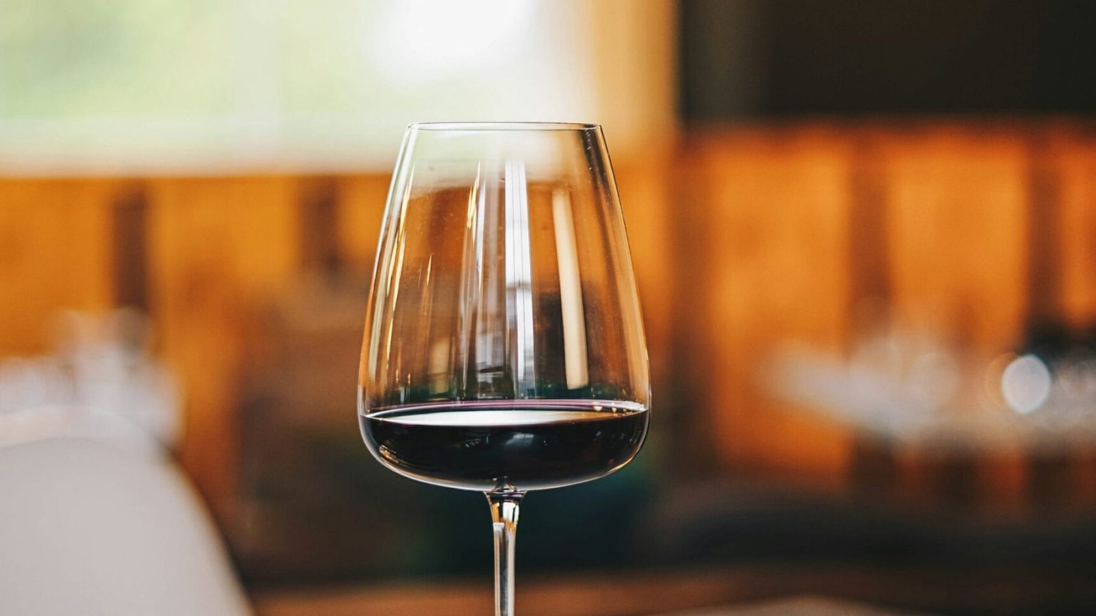 Copa de vino tinto servida en una mesa con iluminacion calida de sobremesa