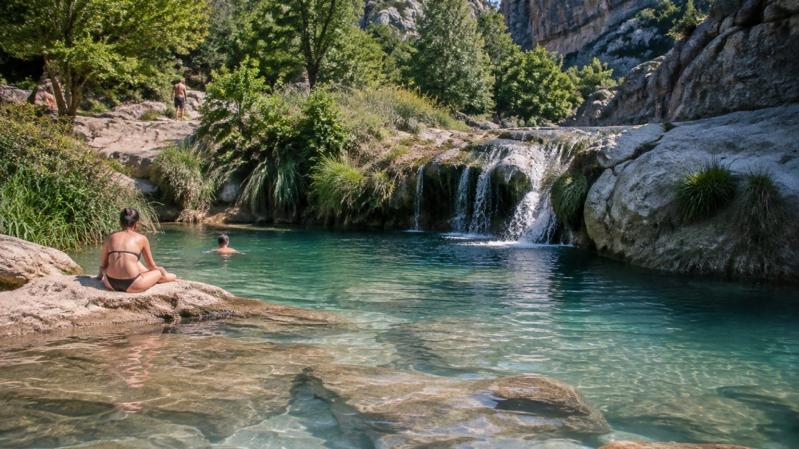 Poza natural de agua turquesa sobre roca caliza con un pequeño salto de agua