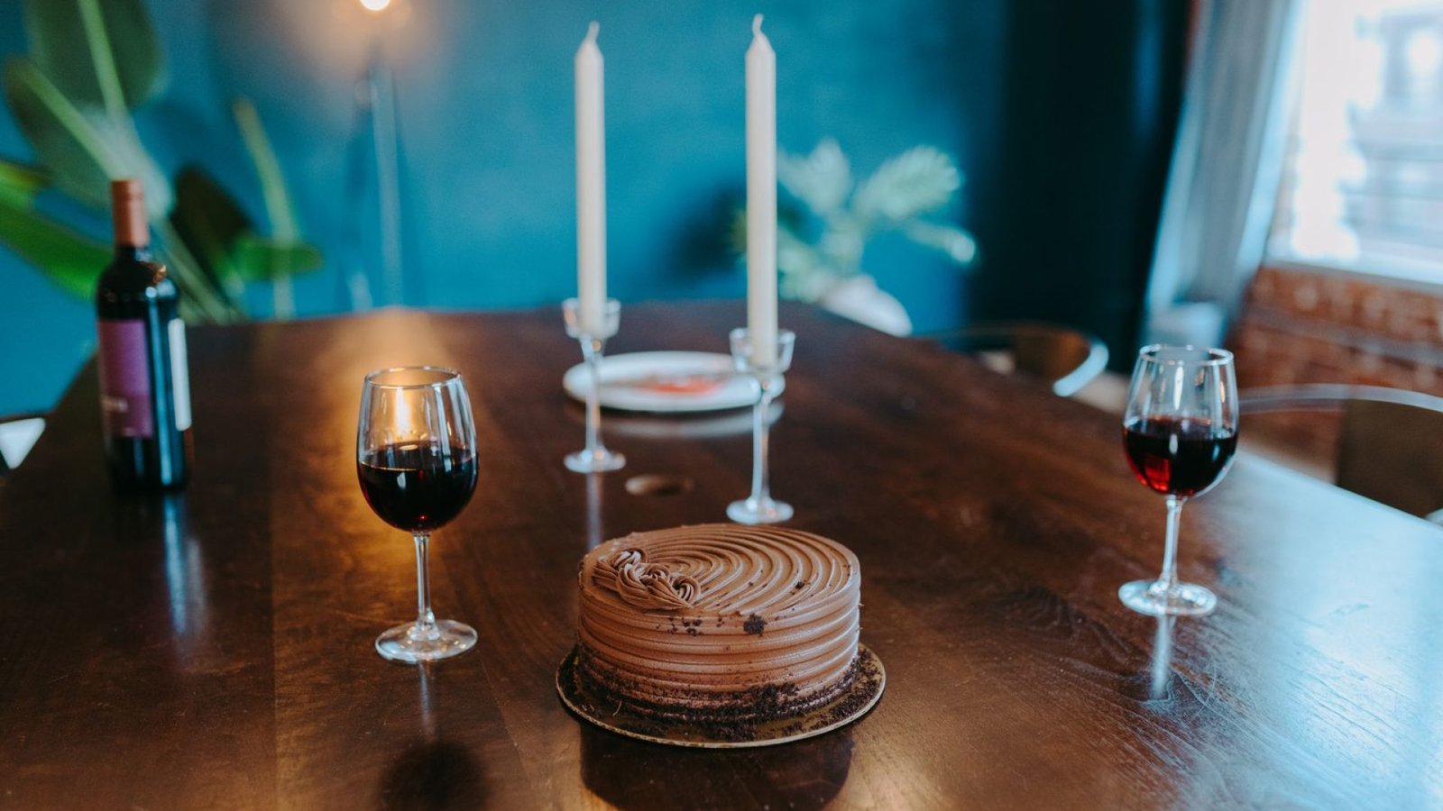Copa de vino tinto junto a una tarta de chocolate en una sobremesa