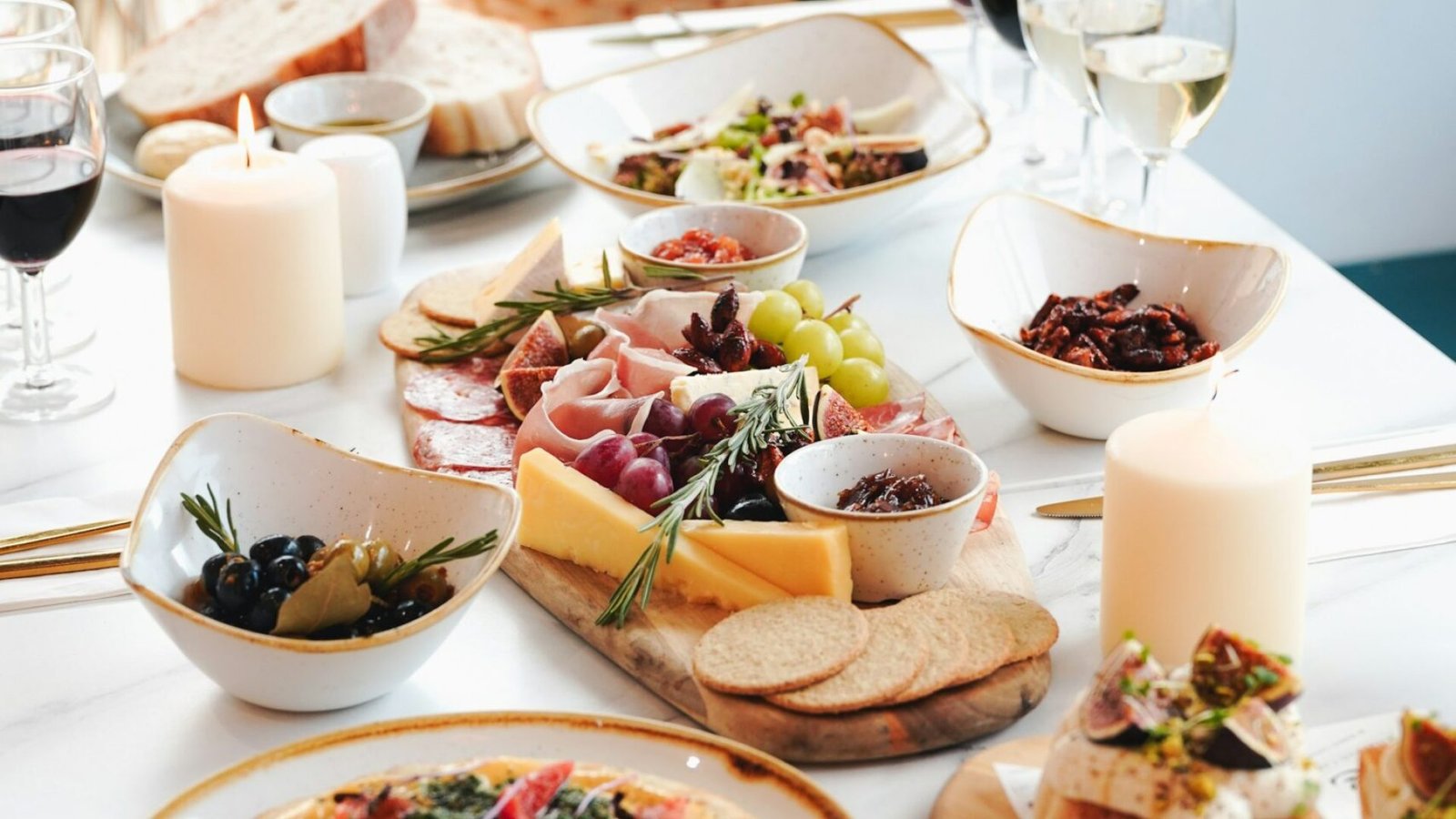 Mesa de picoteo de verano con tabla de embutidos, quesos, pan y copas de vino DO Utiel-Requena